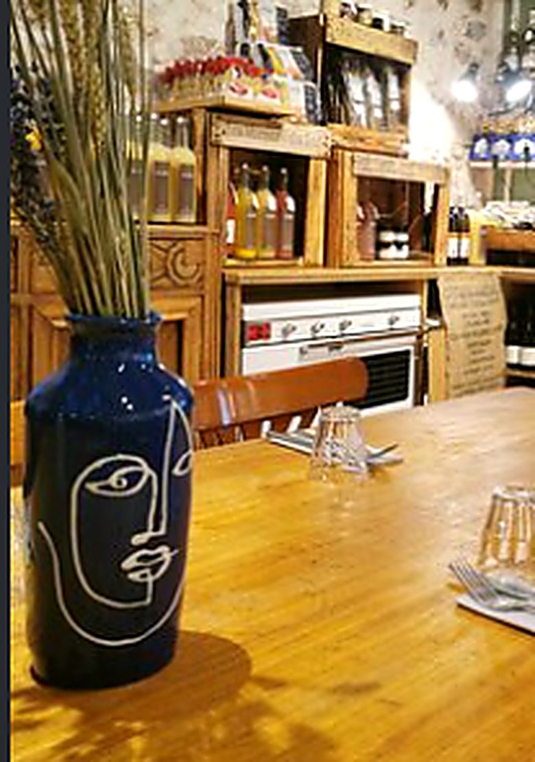 Une table de la salle, murs de pierre et vase bleu